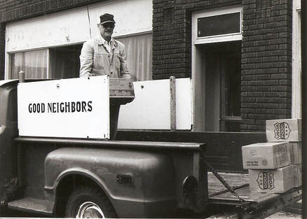 Black and white photo of man loading Good Neighbors truck with food